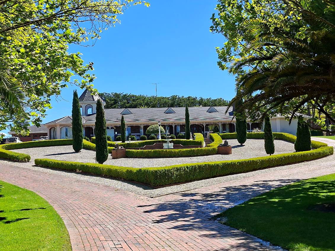 The Reisinger Hall homestead behind clipped hedges and cypress trees
